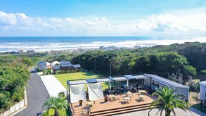 A coastal property with a patio area overlooking the ocean, a grassy lawn, and a view of the beach. - Glamping Kashima 753 (Kashima)