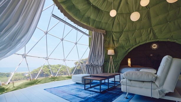 A cozy room with a large window, a sofa, a small table, and hanging lights. - Glamping Kashima 753 (Kashima)