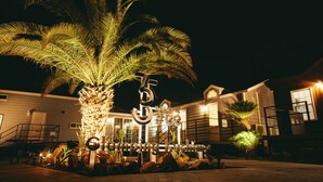A well-lit palm tree in front of a building with a sign that reads "Kashima #CC". - Glamping Kashima 753 (Kashima)