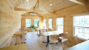 A wooden cabin with multiple tables and chairs, large windows, and a ceiling with exposed beams. - Glamping Kashima 753 (Kashima)