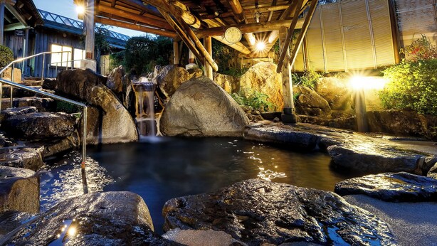 A traditional Japanese onsen with a stone bath, wooden structures, and a waterfall. - Yasuragiso (Amakusa)