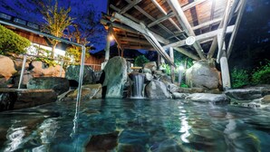 A clear outdoor pool with a waterfall, surrounded by rocks and wooden structures. - Yasuragiso (Amakusa)