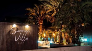 Un senyal de fusta amb el text "Sunrise Villa Oarai" il·luminat a la nit.