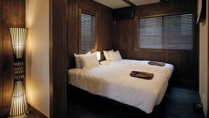 Een slaapkamer met een groot bed, houten wanden en een vloerlamp.