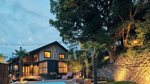 Een modern huis met een zwembad, terras en een stenen muur.