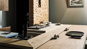 Een moderne keuken met een houten spatwand, een eethoek met een gedekte tafel voor twee en een ingelijste foto aan de muur.