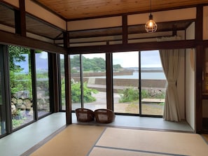 Una habitación con suelo de tatami, ventanas amplias y vistas a la costa.