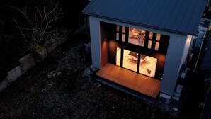 Une maison moderne dotée d’une terrasse en bois et d’une porte vitrée donnant sur un espace repas.