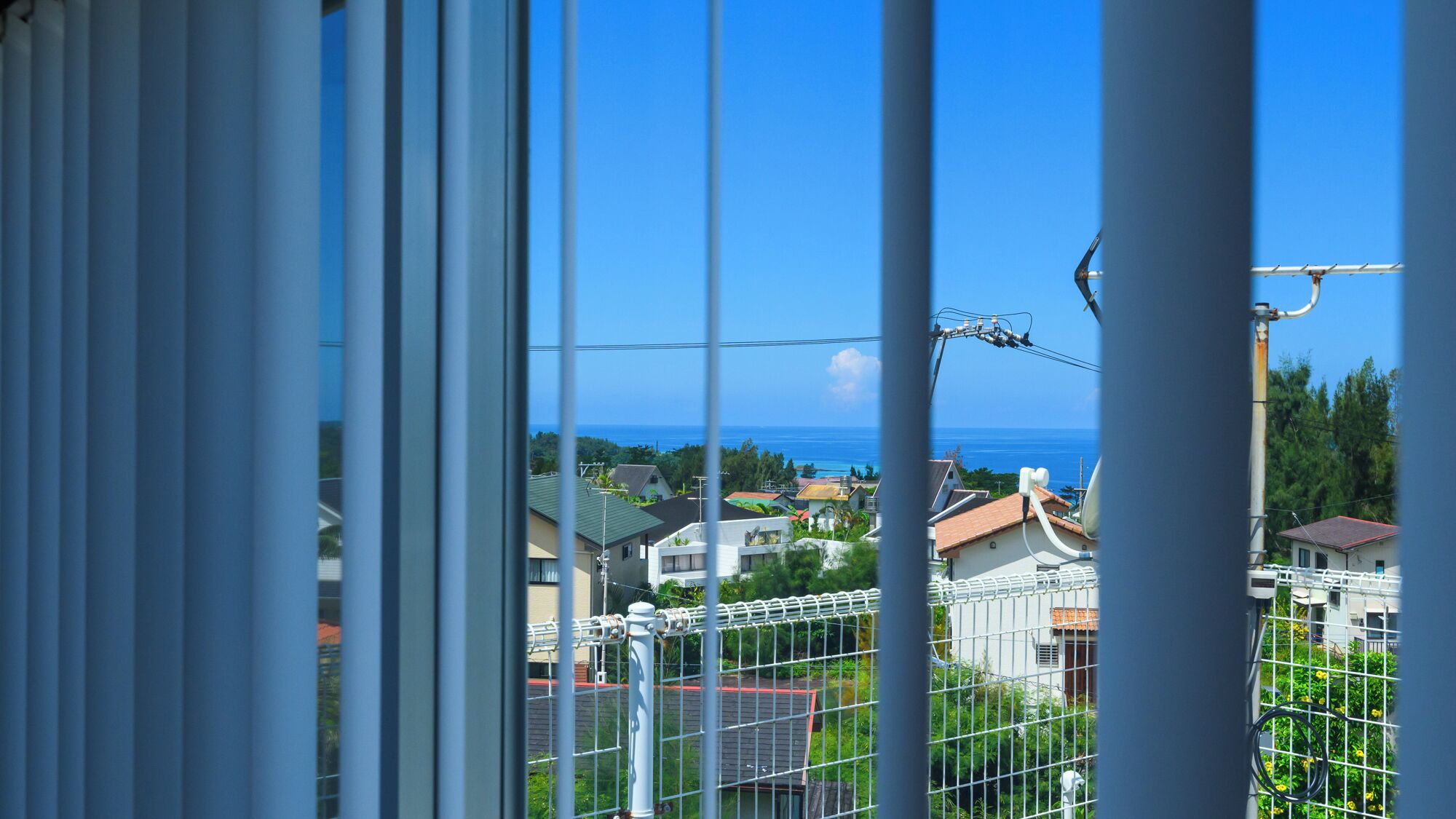 A residential area with houses, a clear blue sky, and a view of the ocean.