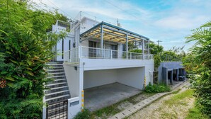A modern building with a covered upper level, a staircase leading to the entrance, and a small garden area. - SEA Eirene Hillstop Onna-son (Onna)