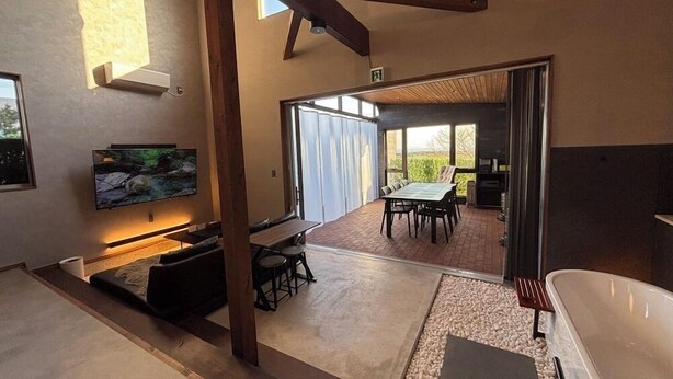 A modern interior with a TV, seating area, and a dining table. - Villa Cortile (Awaji)