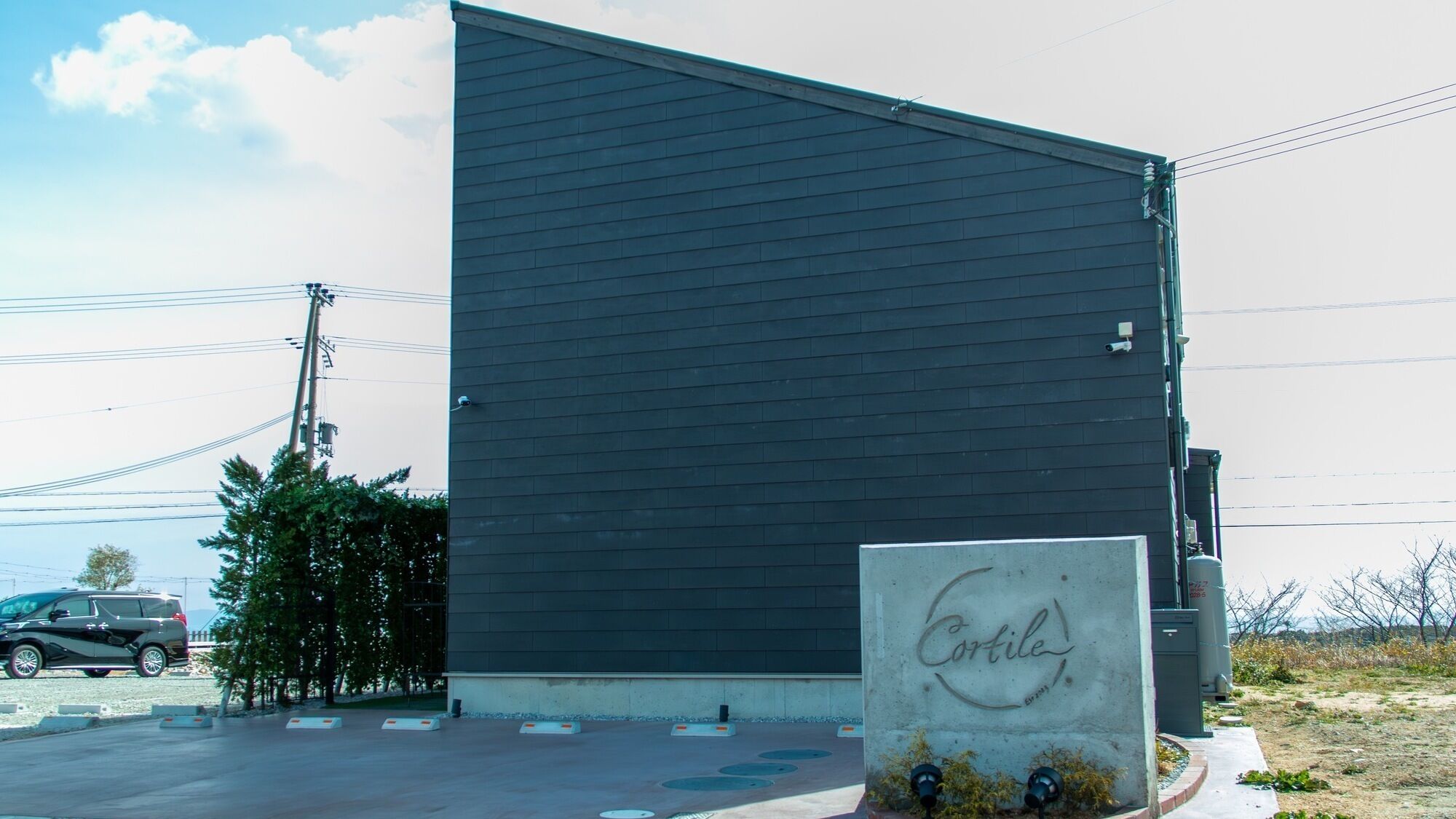 A modern building with a dark facade and a sign reading "Cortile."