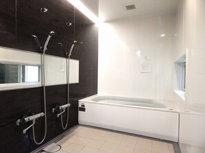 A modern bathroom with a bathtub, a shower with multiple heads, a large mirror, and a window. - Pension Yuuzann (Nagano)