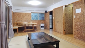 A room with tatami flooring, a low table, a wooden bench, and a sliding door. - Pension Yuuzann (Nagano)