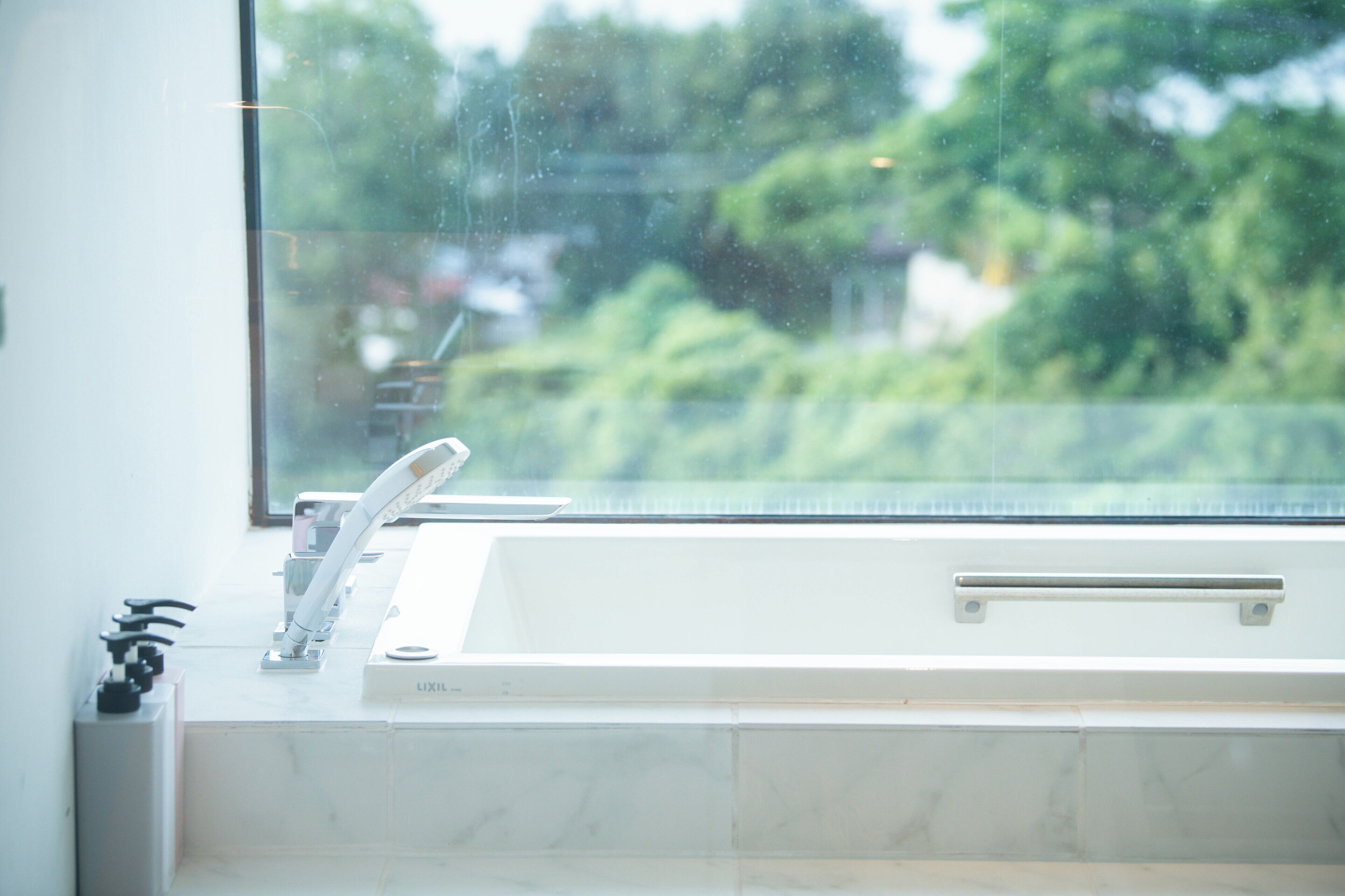 Un baño con lavamanos blanco, espejo y ventana.