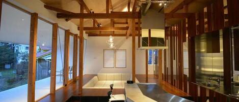 A modern kitchen with wooden beams, a large island, and a stainless steel refrigerator.