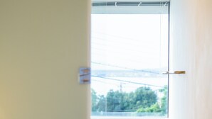 Een modern interieur met een trap naar een balkon met uitzicht op groen en een waterpartij.