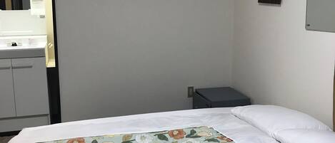 A bedroom with a bed, a bedside table, an air conditioning unit, and a mirror.
