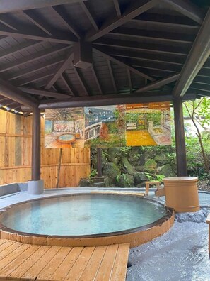 Un espace de sources chaudes doté d’une terrasse en bois, d’un bassin en pierre et d’une clôture en bois.