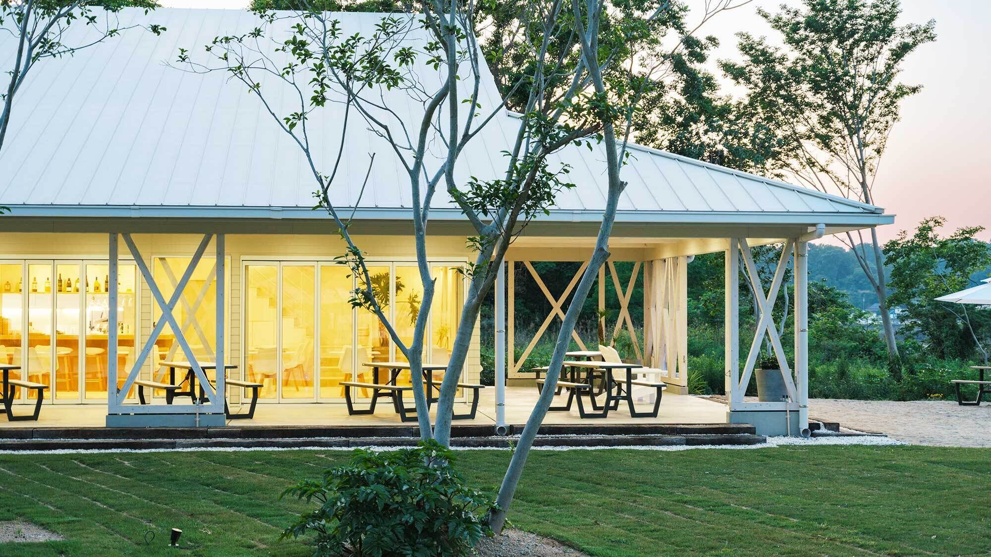 Un área de comedor al aire libre cubierta con mesas de picnic y un edificio acristalado al fondo.