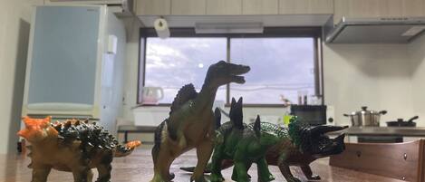 A kitchen with cabinets, a window, and a countertop with dinosaur figurines.