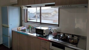 Kompakti keittiö, jossa on puukaapit, mikroaaltouuni, vedenkeitin ja liesi.