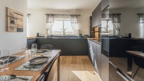 Eine moderne Küche mit Essbereich, großen Fenstern mit Vorhängen und Blick auf die Stadt.