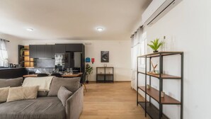 Ein modernes Wohnzimmer mit einem grauen Sofa, Holzboden und einem schwarzen Metallregal.