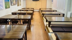 Un aula con mesas y sillas de madera, una pizarra y carteles educativos en las paredes.