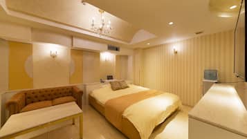 A hotel room with a bed, a sofa, a desk, and a water dispenser.