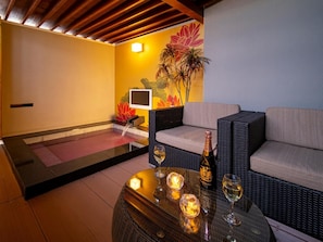 A room with a sofa, a table with candles and a bottle, a TV, and a decorative wall. - Hotel Noblesse (Kobe)