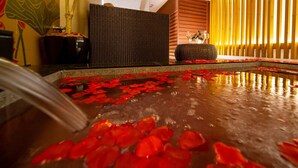 A spa area with a water feature, a wicker chair, and a wooden wall. - Noblesse (Kobe)