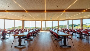 A conference room with long tables and chairs, large windows, and a wooden ceiling. - Lectore Hayama Shonan Kokusai Mura (Hayama)