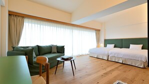 A hotel room with a green sofa, two single beds, a wooden coffee table, and a small side table. - Lectore Hayama Shonan Kokusai Mura (Hayama)