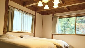 Una habitación con dos camas, vigas de madera y ventanas amplias con cortinas.
