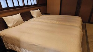 A neatly made bed with a wooden headboard and a large window with blinds. - Miyama Resort Kayabukitei (Nantan)
