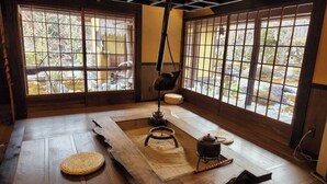 A traditional Japanese room with tatami flooring, a shoji screen, a hanging lamp, and a small stove. - Miyama Resort Kayabukitei (Nantan)