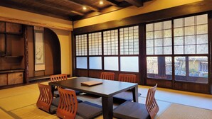 A traditional Japanese-style room with tatami flooring, a low table, and wooden chairs. - Miyama Resort Kayabukitei (Nantan)