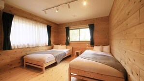 A wooden cabin bedroom with two beds, a window, and a small table. - Cottage Oyumino (Chiba)