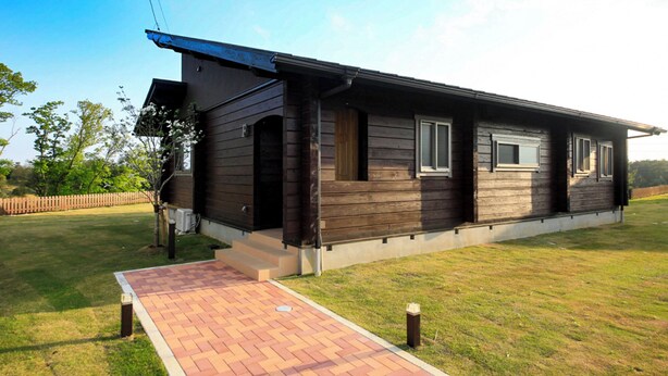 A single-story wooden house with a covered porch, a brick pathway leading to the entrance, and a fenced yard. - Cottage Oyumino (Chiba)