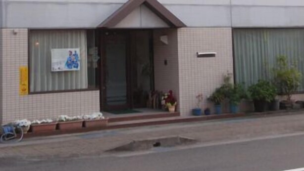 Un edificio de dos pisos con techo plano, ventanas grandes y fachada de tejas.