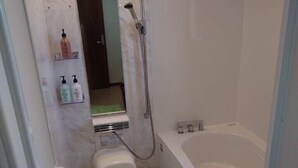 A bathroom with a toilet, a shower, and a bathtub. There are toiletries on a shelf. - Ann Villa (Nakijin)