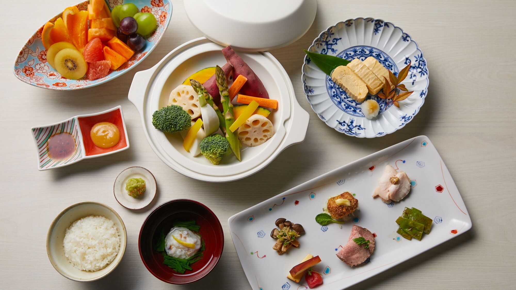 A variety of dishes including sushi, rice, and vegetables on a table.