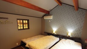 Una habitación con dos camas individuales, vigas de madera en el techo, una ventana y un equipo de aire acondicionado.