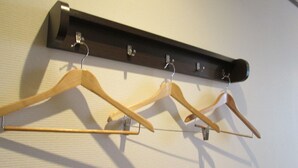 A wooden coat rack with four hangers against a wall. - Business Hotel Step In Haramachi (Minamisoma)