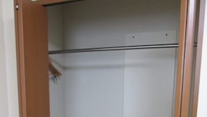A walk-in closet with wooden doors, a pink basket, and a white panel on the wall. - Business Hotel Step In Haramachi (Minamisoma)