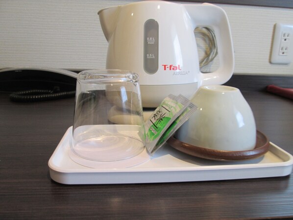 A white tray with a glass, a packet, and a white mug on a dark wooden table.