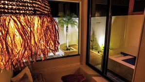 Una habitación con un ventanal grande, un taburete de madera y una lámpara colgante decorativa.