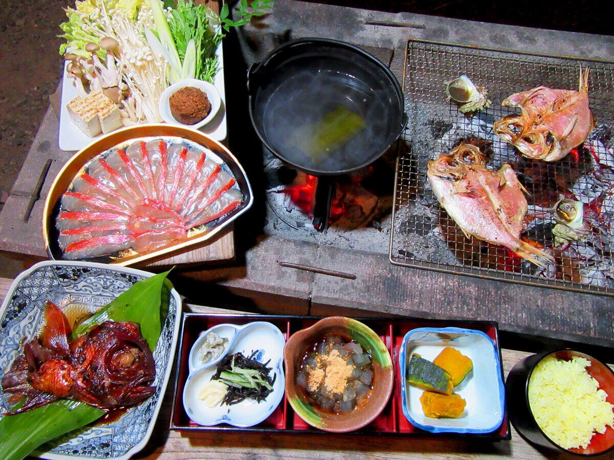 A variety of dishes including grilled fish, vegetables, and rice, served on a wooden table.