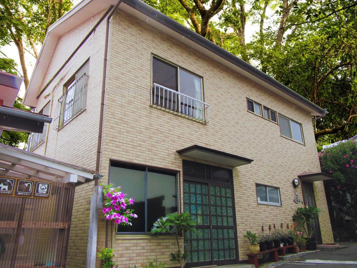 A two-story brick house with a balcony, large windows, and a green door.